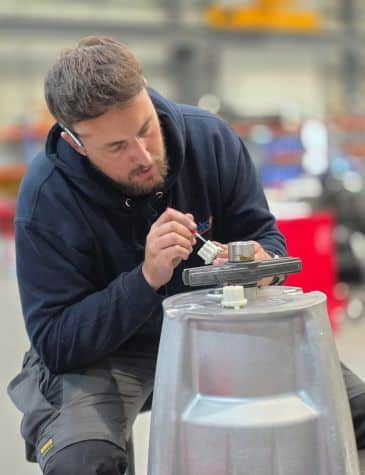 Engineer performing pump repair at Neutronic Technologies workshop, applying precision work on a pump component mounted on a metallic base.