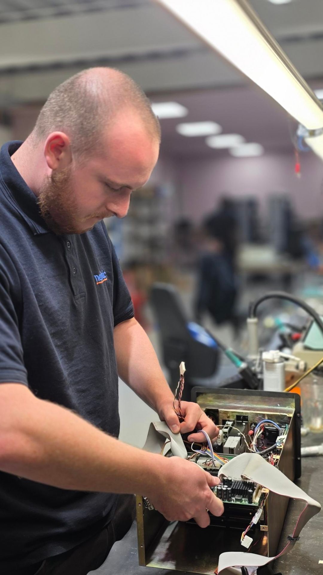 CNC HMI Repairs in progress at Neutronic Technologies electronic workshop, showing an engineer working on internal circuit components of an industrial control unit.